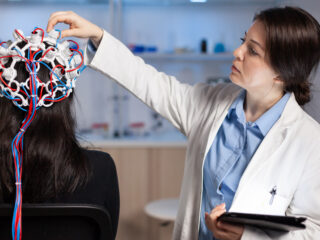 Doctor conducting a brain activity test on a patient using EEG equipment.