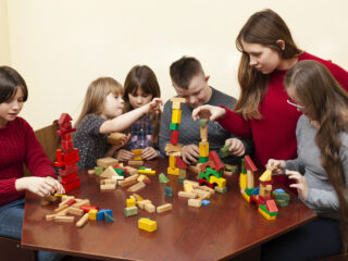 Children and teacher engaging in a collaborative block-building activity.