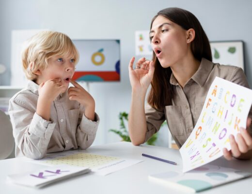 Speech therapist teaching phonetics to young boy in classroom