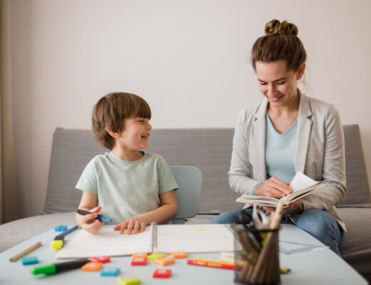 A smiling child engages with a supportive adult in a learning environment, reflecting positive autism therapy and educational support.