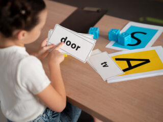 A young child is working with flashcards displaying simple words like "door" and "tv" to support dyslexia learning.